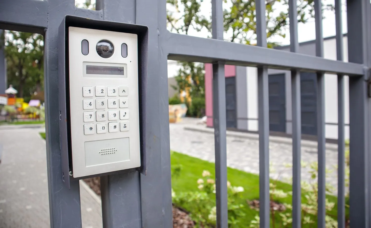 Intercom keypad on the post of a gray metal driveway gate