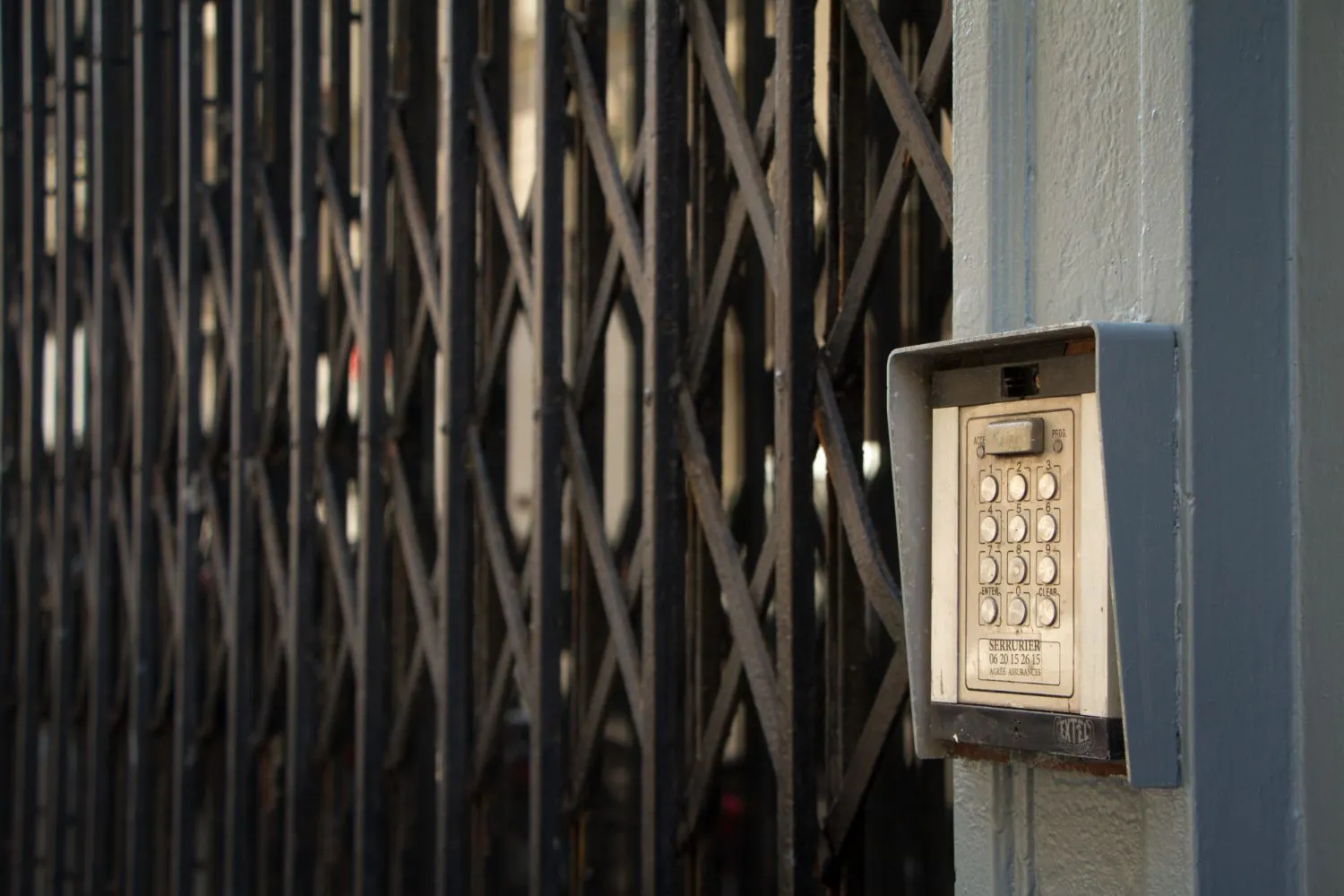 Keypad access control mounted beside a black security gate