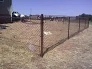 Black chain link fence installed across a dry, open yard