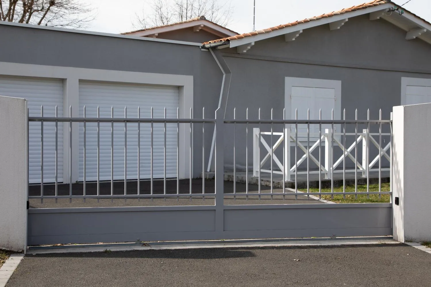 Metal sliding gate in front of a house and garage