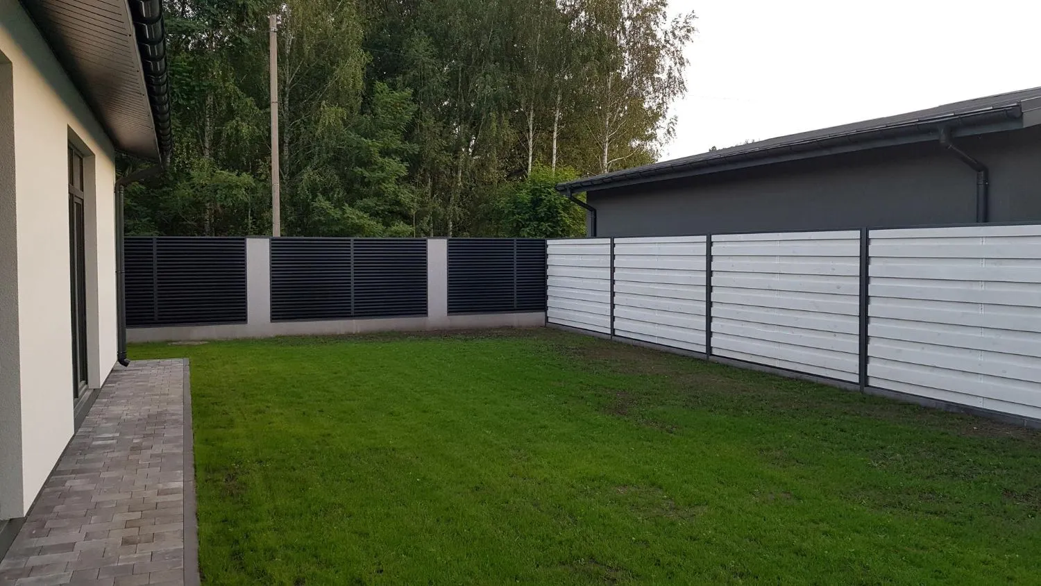 Modern gray horizontal privacy fence around a backyard lawn