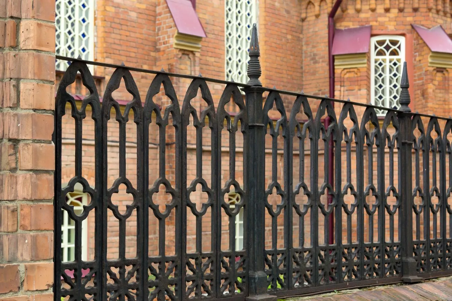 Black ornamental iron fence in front of a brick building
