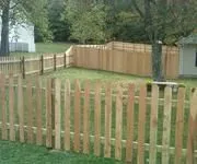 A wooden picket fence surrounds a lush green yard.