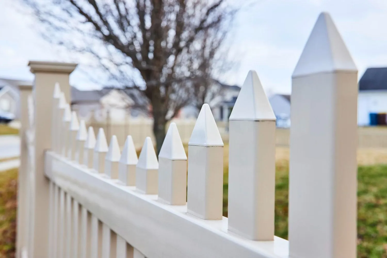 Close-up of white vinyl picket fence with pointed pickets