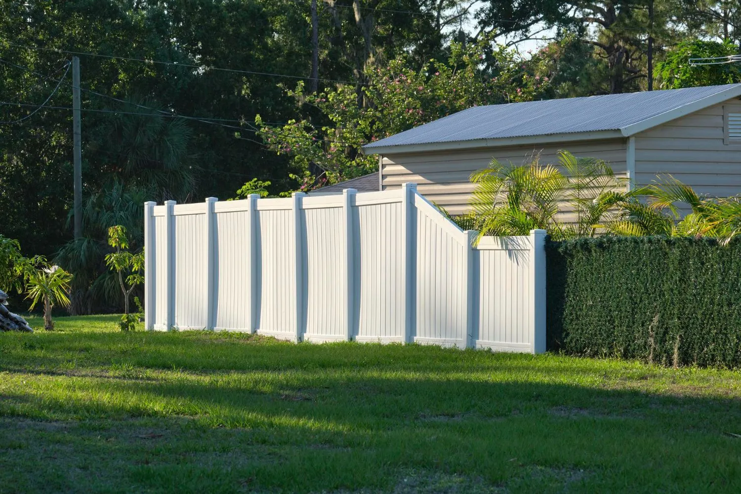 White vinyl privacy fence around a sunny backyard