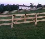 Three-board wood fence with a matching gate across a grassy yard