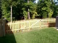 A wooden picket fence surrounds a lush green yard.